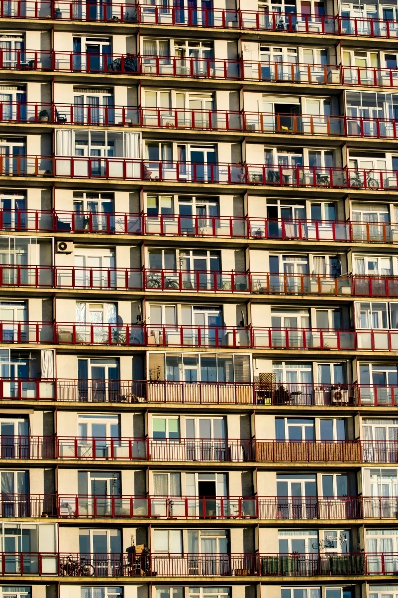Repeating balconies with red railings across an apartment block